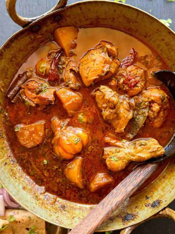 Bihari chicken curry served in a kadhai with roti and onions on the side