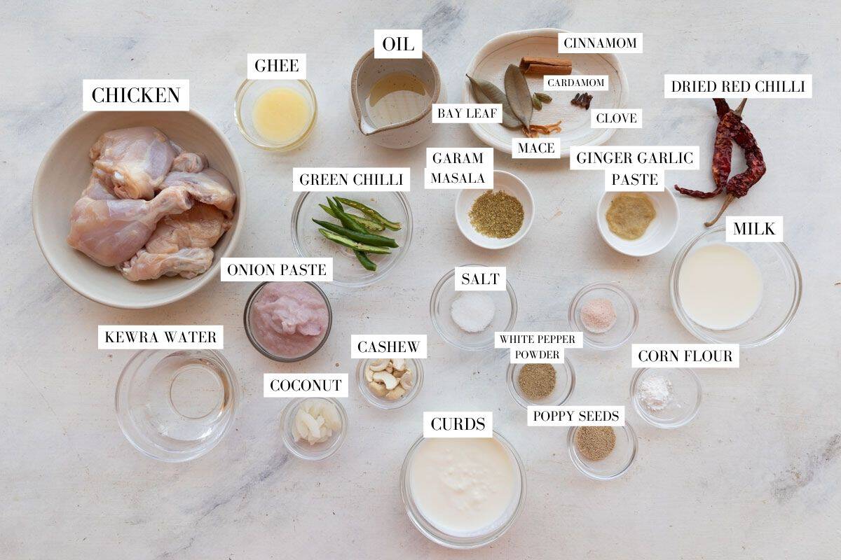Ingredients for chicken rezala in bowls on a white surface