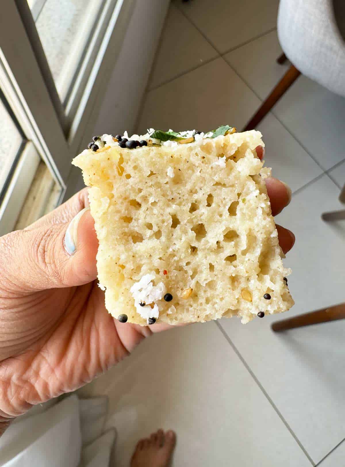 Close up of a piece of jowar dhokla to show the spongy and airy texture of the dhokla