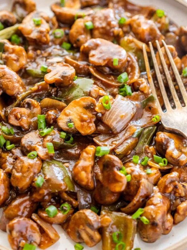 Mushroom chilli on a white plate with a fork on the side