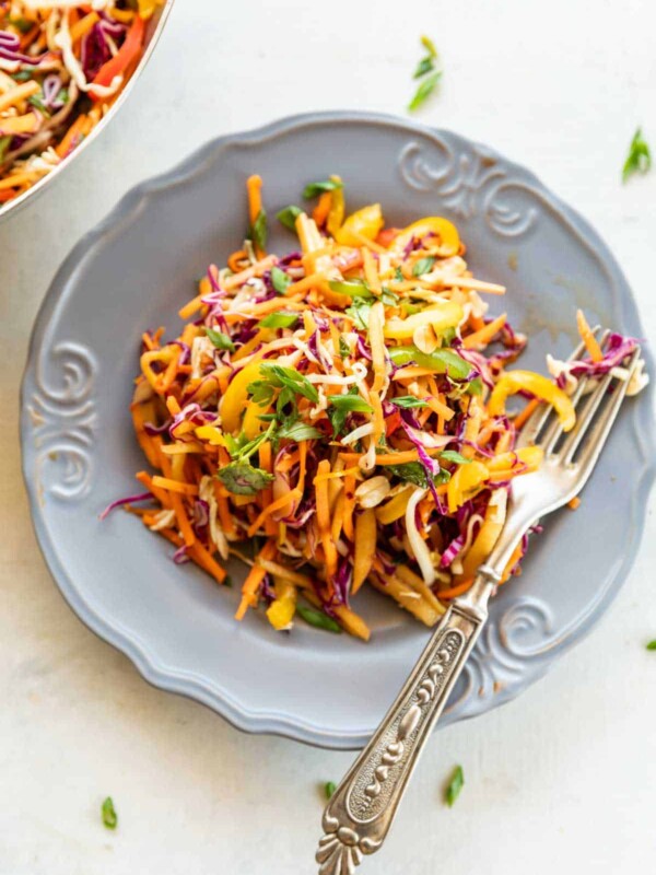 Asian Slaw in a grey bowl with fork on a white background