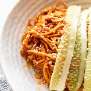 bibim guksu garnished with cucumber in a white bowl