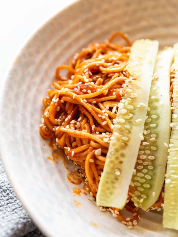 bibim guksu garnished with cucumber in a white bowl
