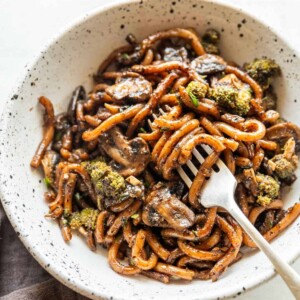 Black pepper udon noodles served in a white bowl with fork