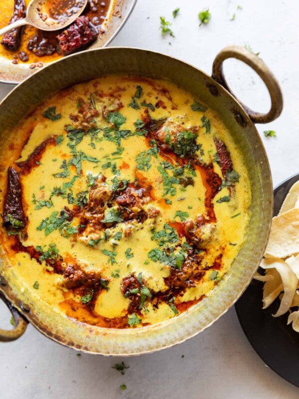 vibrant kadhi pakora garnished with a tadka and coriander leaves, served in a copper handi