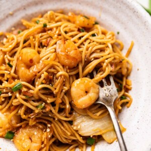 chilli garlic prawn noodles served in a white bowl with a fork