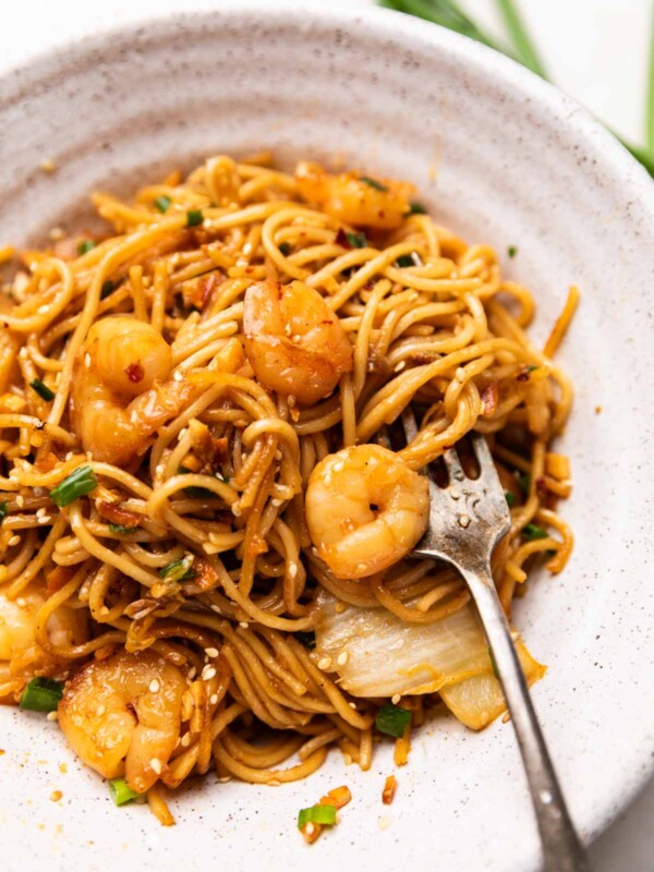 chilli garlic prawn noodles served in a white bowl with a fork