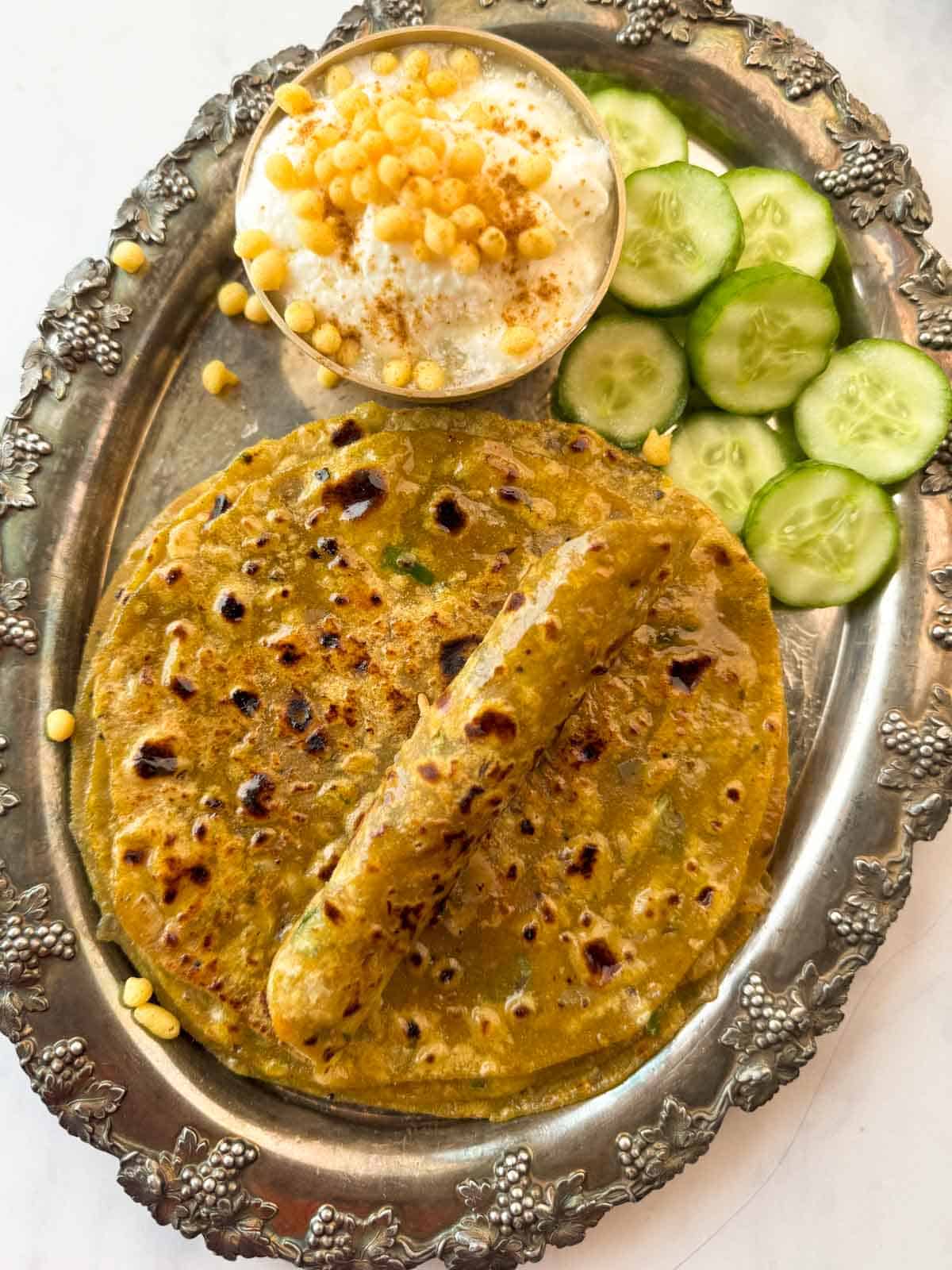 Dal paratha served on a platter with curd and cucumbers