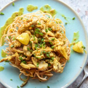 lemon chicken served on a bed of fried noodles on a blue plate with fork
