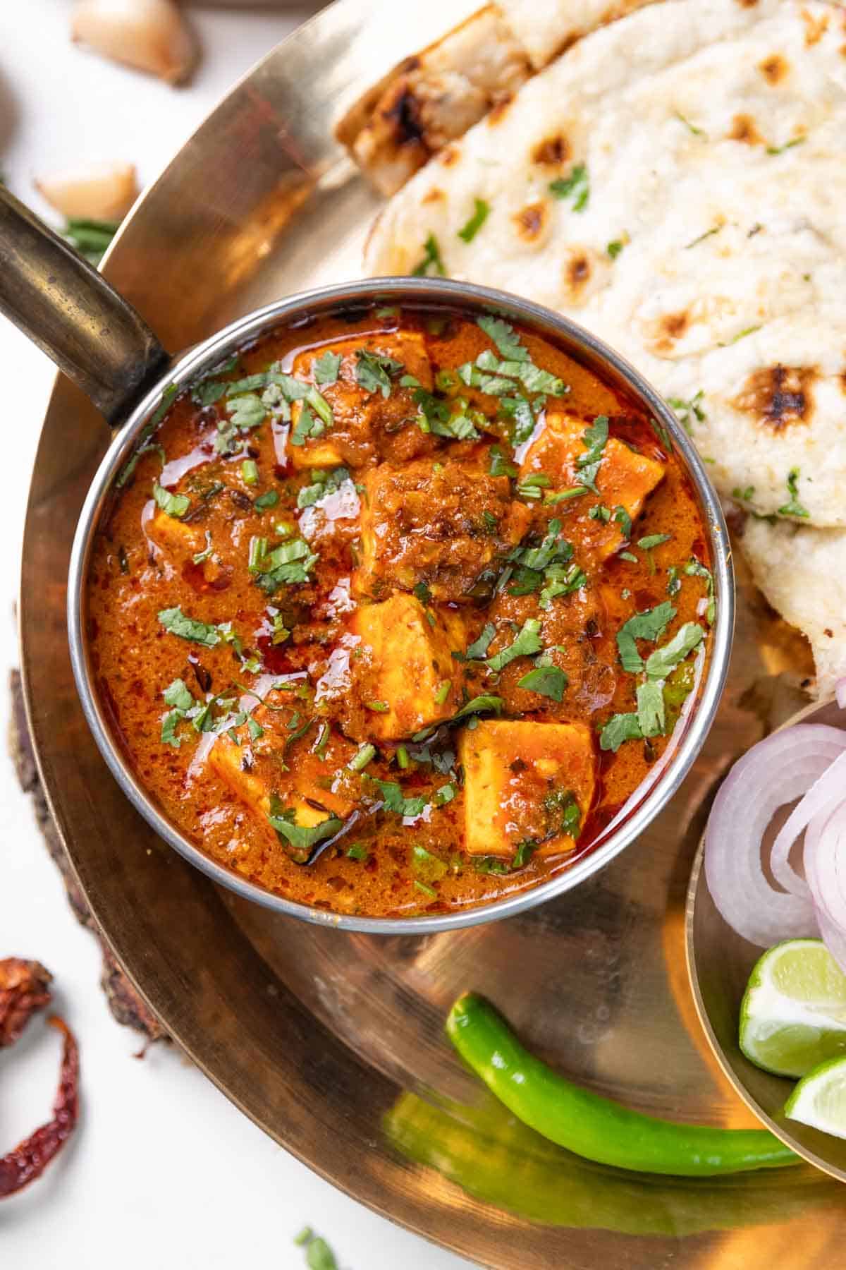 dhaba style paneer masala served with naan, green chilli, onion slices and lemon