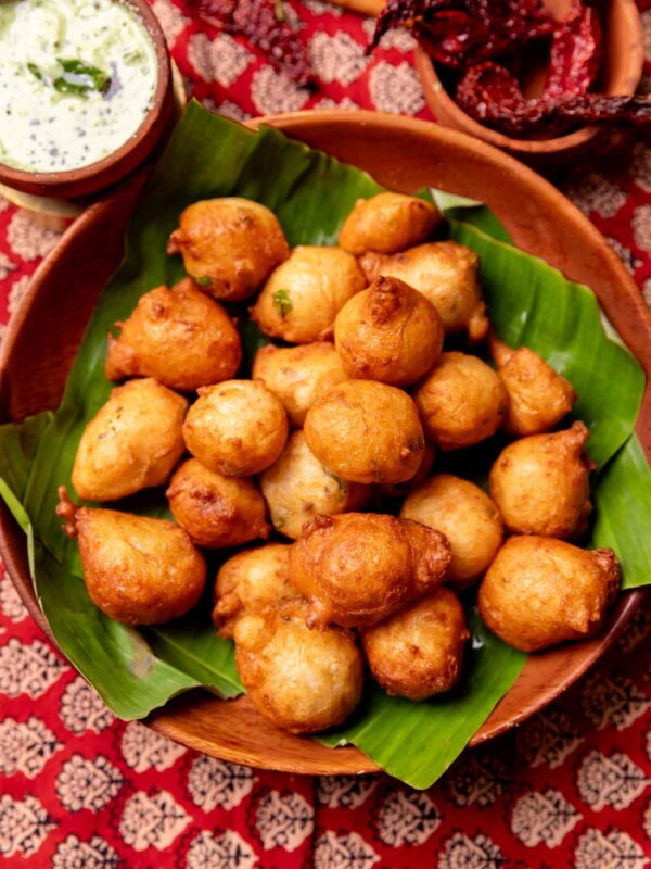 an image of crunchy goli bajji placed on a leaf and served in a platter with coconut chutney