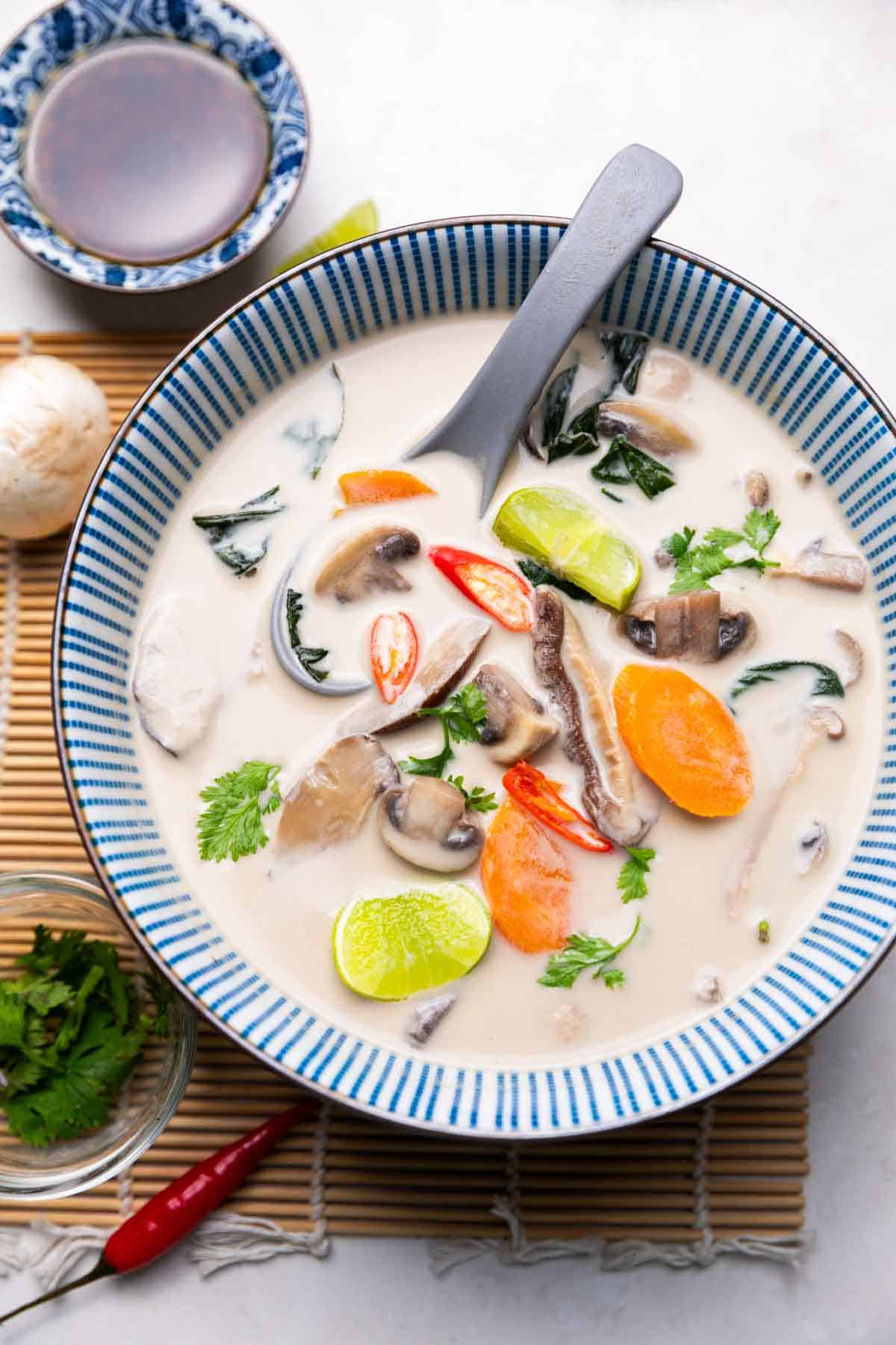 vegetarian tom kha soup served in a bowl with a soup spoon