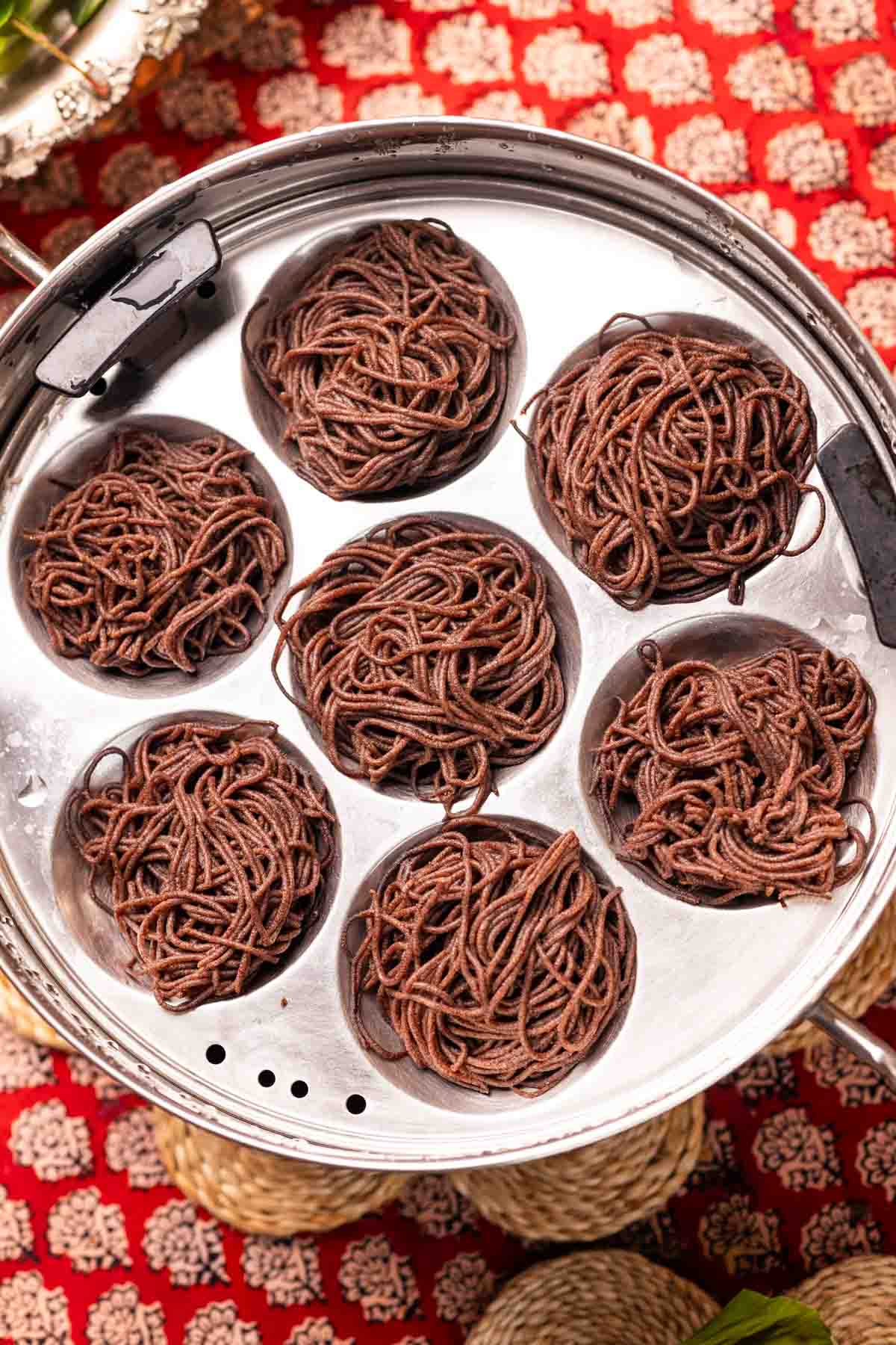 freshly steamed ragi idiyappams placed in a in steamer
