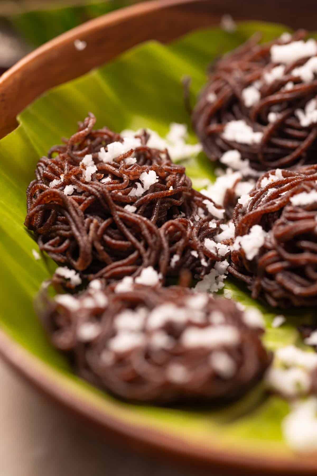 ragi idiyappam garnished with coconut and served on a leaf platter