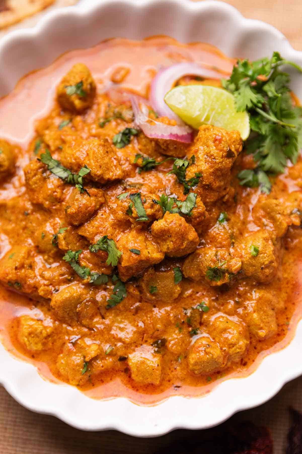 soya curry served in a bowl with onion, lemon and coriander