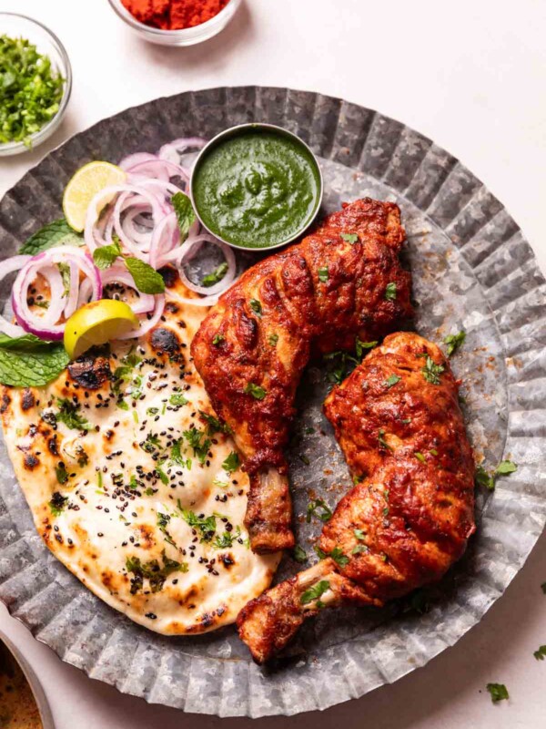 tandoori chicken served on a platter with accompaniments