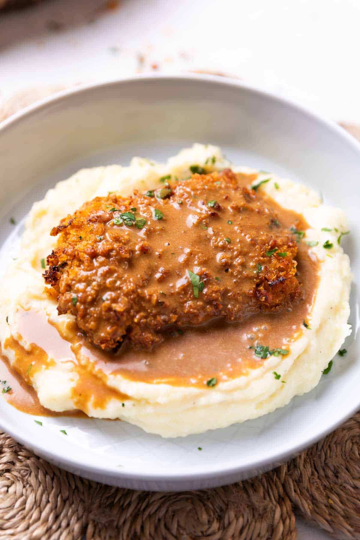 air fryer fried chicken served on a bed of creamy mashed potato with gravy on top