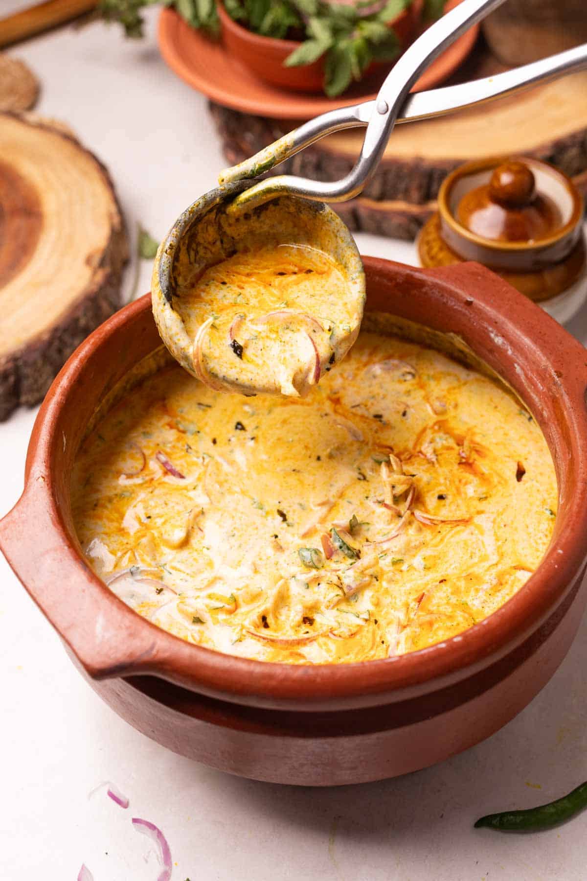 an image of dahi tadka served in an earthen bowl