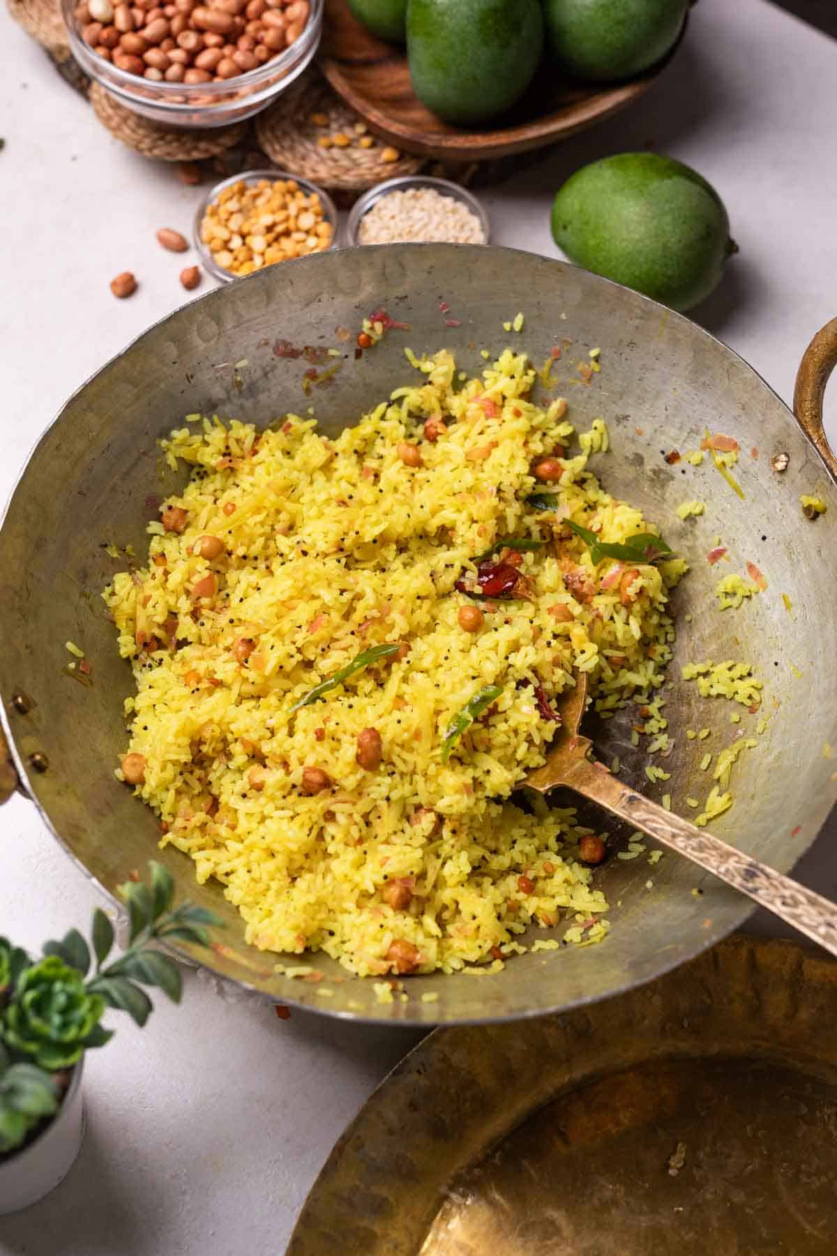 freshly cooked raw mango rice in a kadai with ladle