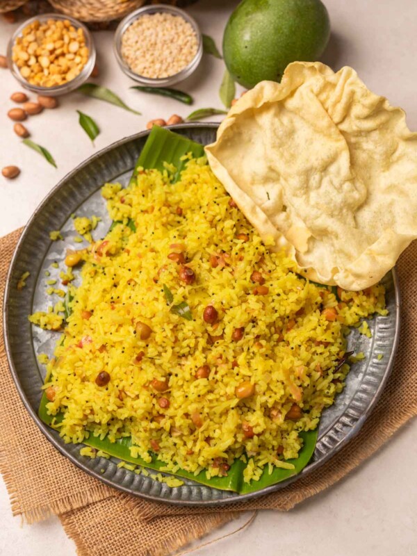 raw mango rice served on a round metal plate with pappadum