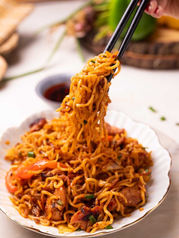 an image of chilli chicken noodles picked up with a pair of chopsticks