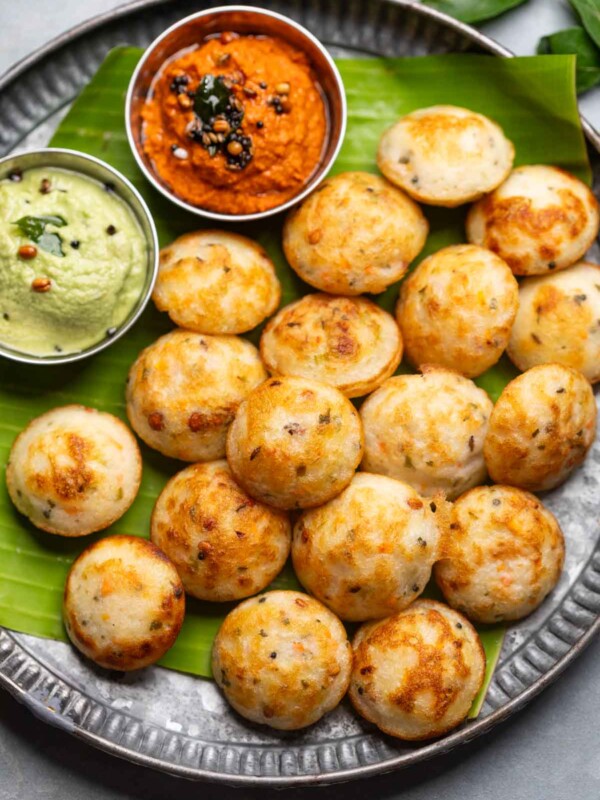 Freshly cooked paniyaram served on a banana leaf platter with accompaniments
