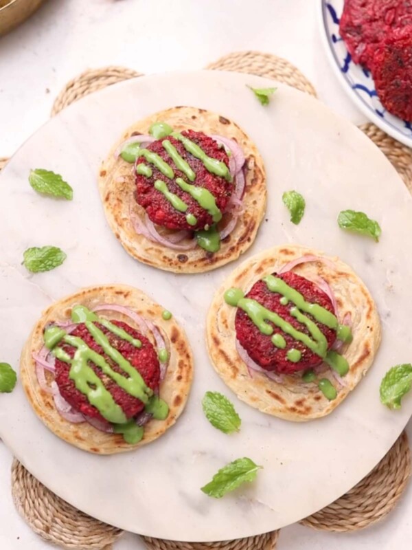Beetroot tikki served on a flaky paratha with onion rings and garnished with green chutney