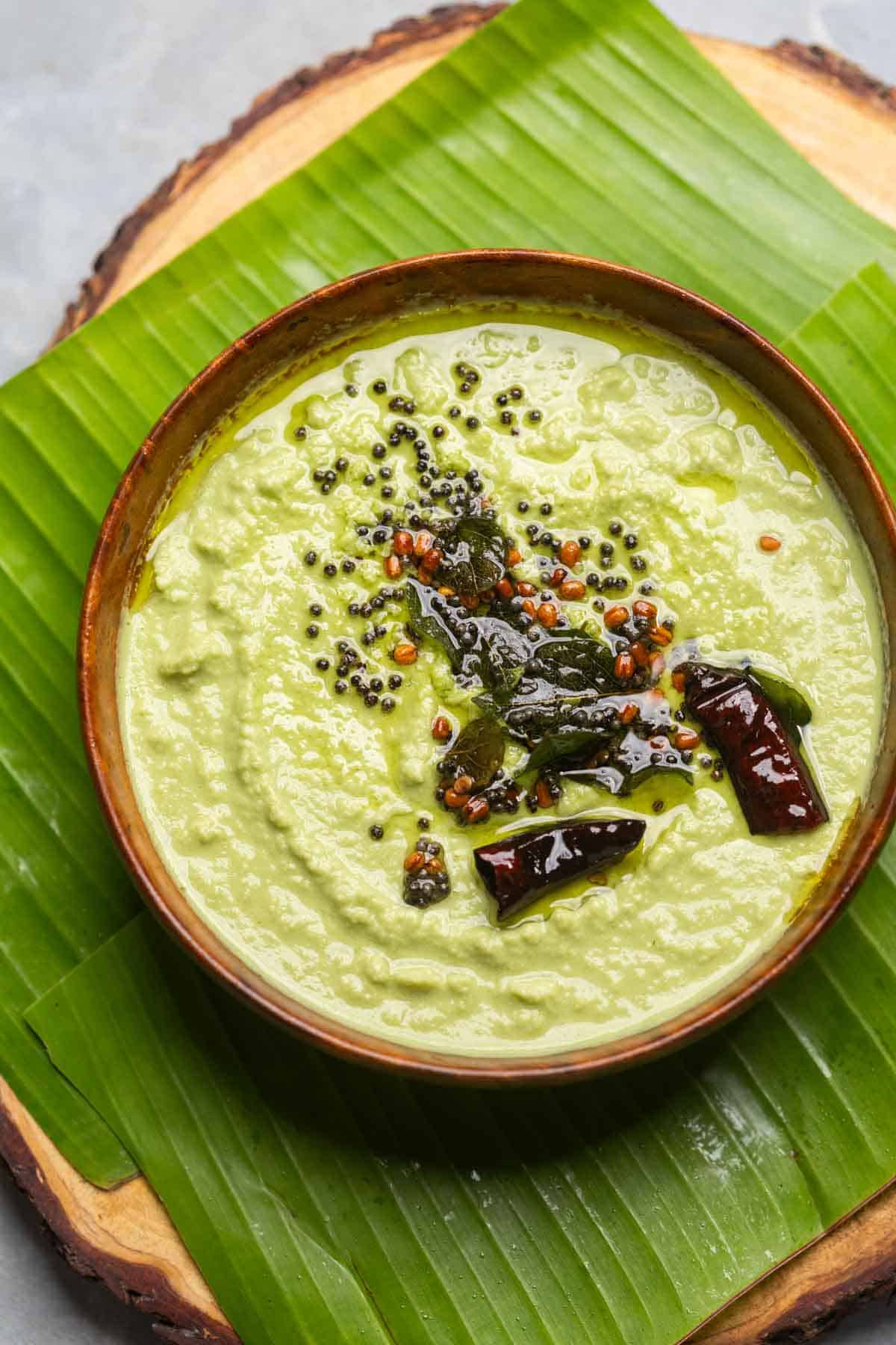 an image of coconut chutney made served in a bowl placed over a banana leaf platter