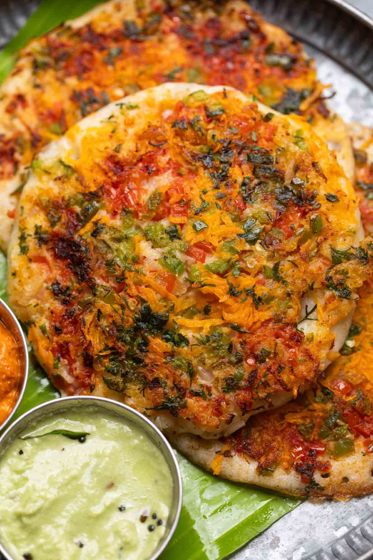 uttapams served with chutneys on a banana leaf platter
