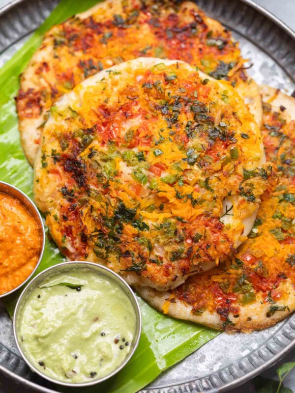 uttapams served with chutneys on a banana leaf platter