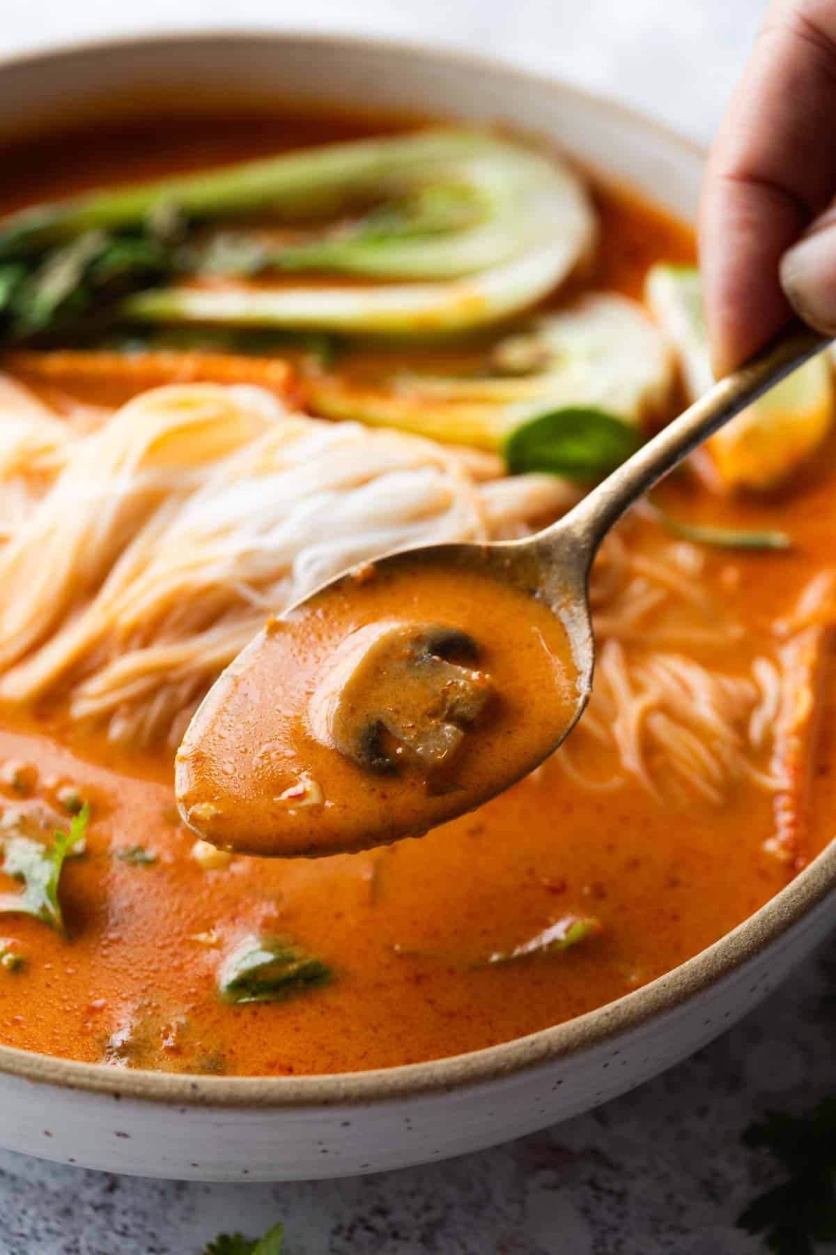 close up image of thai curry soup scooped up in a spoon to show it's creamy texture