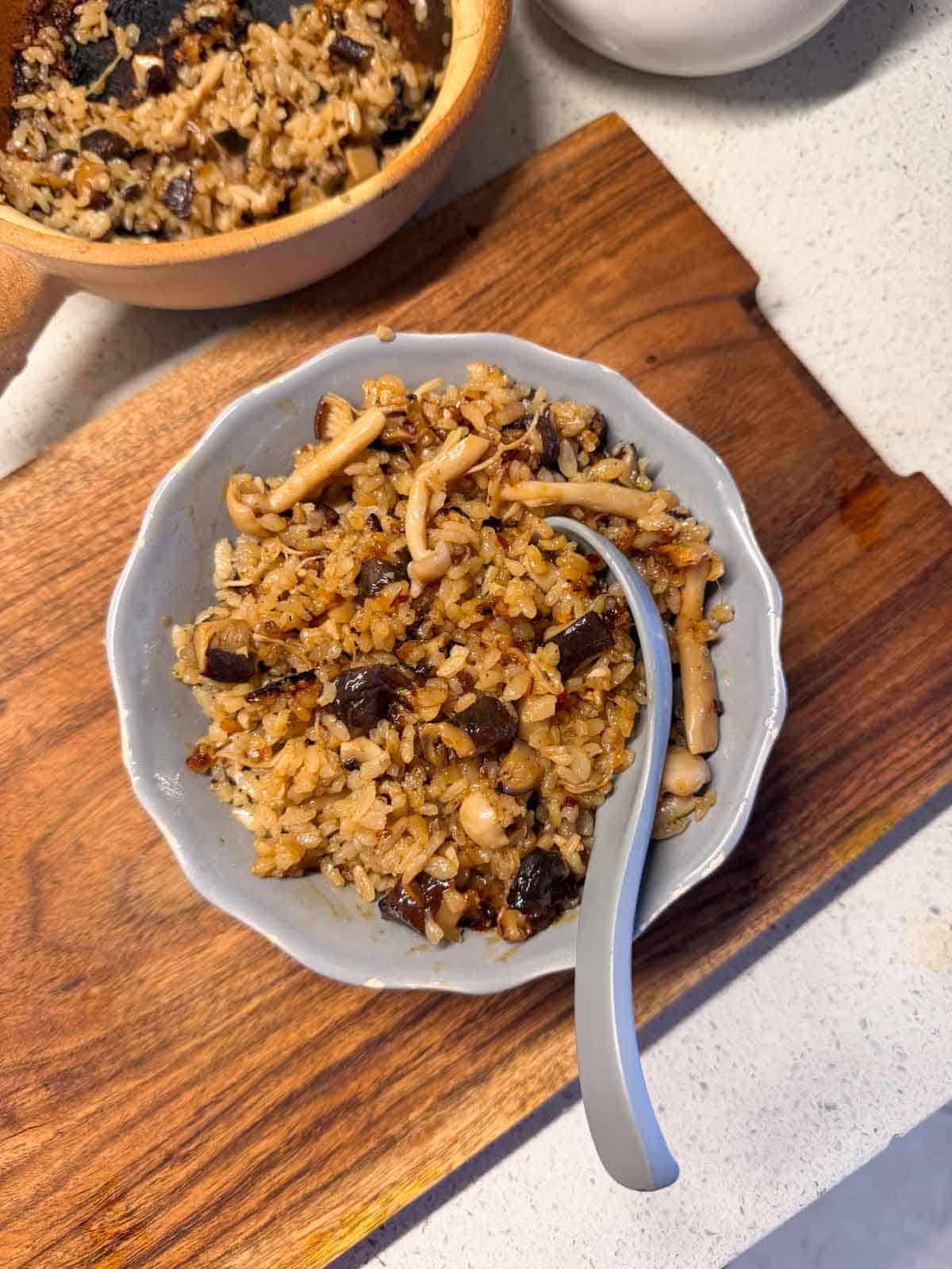 claypot mushroom rice served in a bowl with spoon