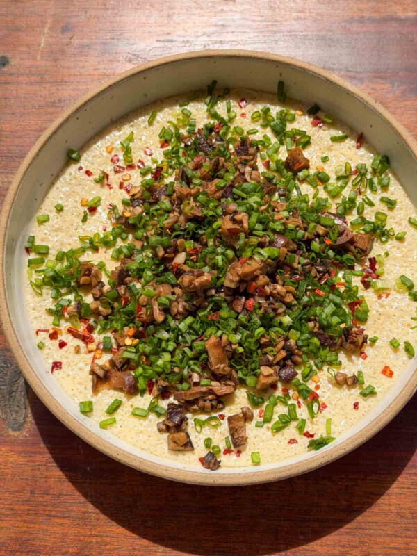 an image of chinese steamed eggs garnished with mushroom and spring onion ready to be eaten