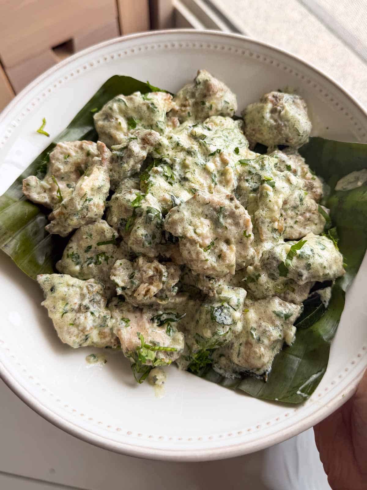 creamy coriander chicken served on a white plate